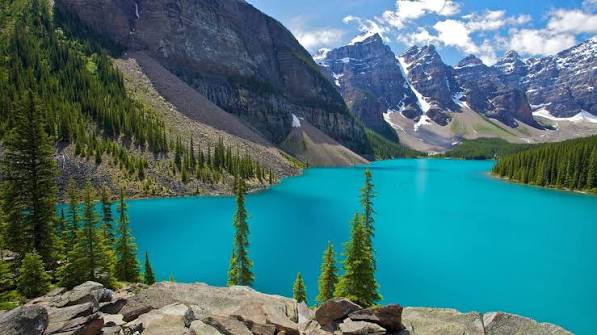 Lago de água turquesa cercado por montanhas com neve, no Canadá